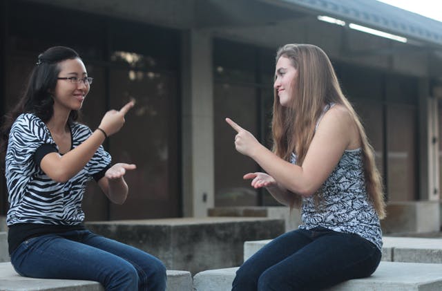 Joanna Byun, left, signs with her friend Laura Hogan. Byun is one of only three deaf students at UF who use classroom interpreters.
