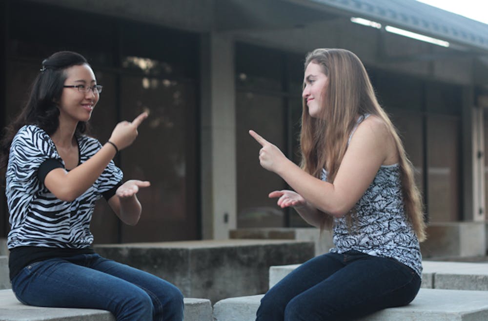 <p>Joanna Byun, left, signs with her friend Laura Hogan. Byun is one of only three deaf students at UF who use classroom interpreters.</p>