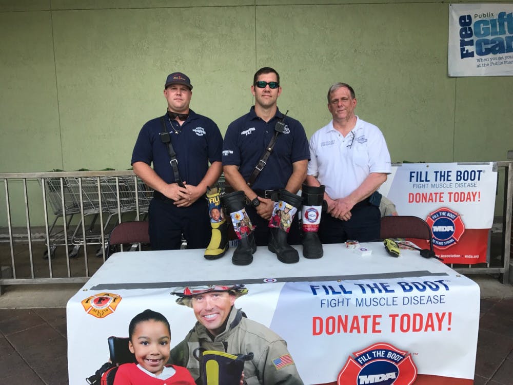 Gainesville firefighters Josh Rodgers (left), Adam Whitehead (middle) and Terry McCarthy (right) stand with their cash-stuffed boots outside of Publix, located at 1302 N Main St. The Fill the Boot campaign raised $22,333.44 for the Muscular Dystrophy Association, which works to find a cure for muscular dystrophy, a disease that causes progressive muscle weakness.