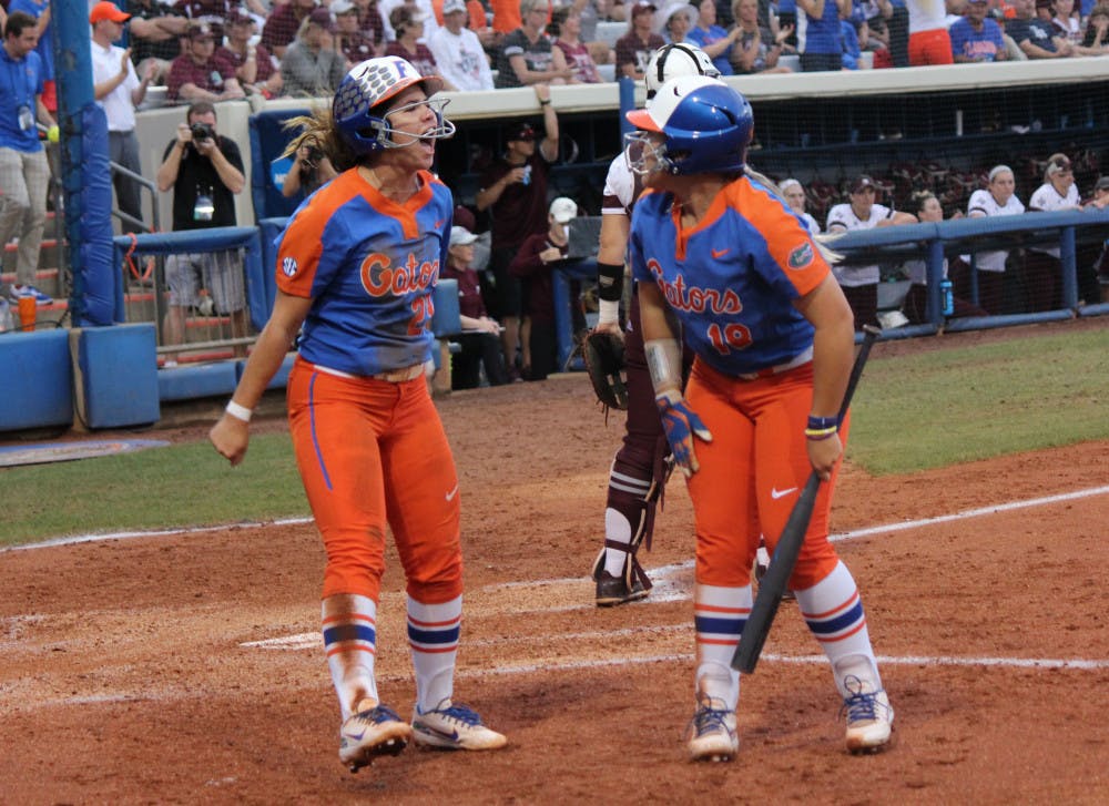Senior third baseman Nicole DeWitt (left) and junior right fielder Amanda Lorenz (right) celebrate after scoring runs against Texas A&amp;M on Friday. They and the No. 4 Gators will face No. 9 Georgia at the Women’s College World Series in Oklahoma City.