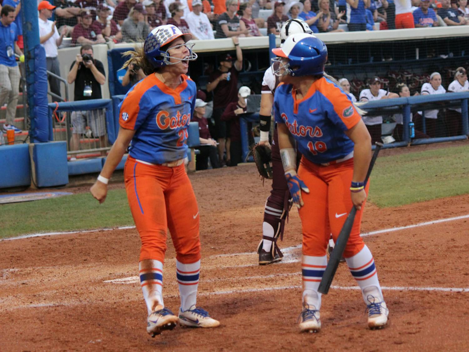 Senior third baseman Nicole DeWitt (left) and junior right fielder Amanda Lorenz (right) celebrate after scoring runs against Texas A&amp;M on Friday. They and the No. 4 Gators will face No. 9 Georgia at the Women’s College World Series in Oklahoma City.