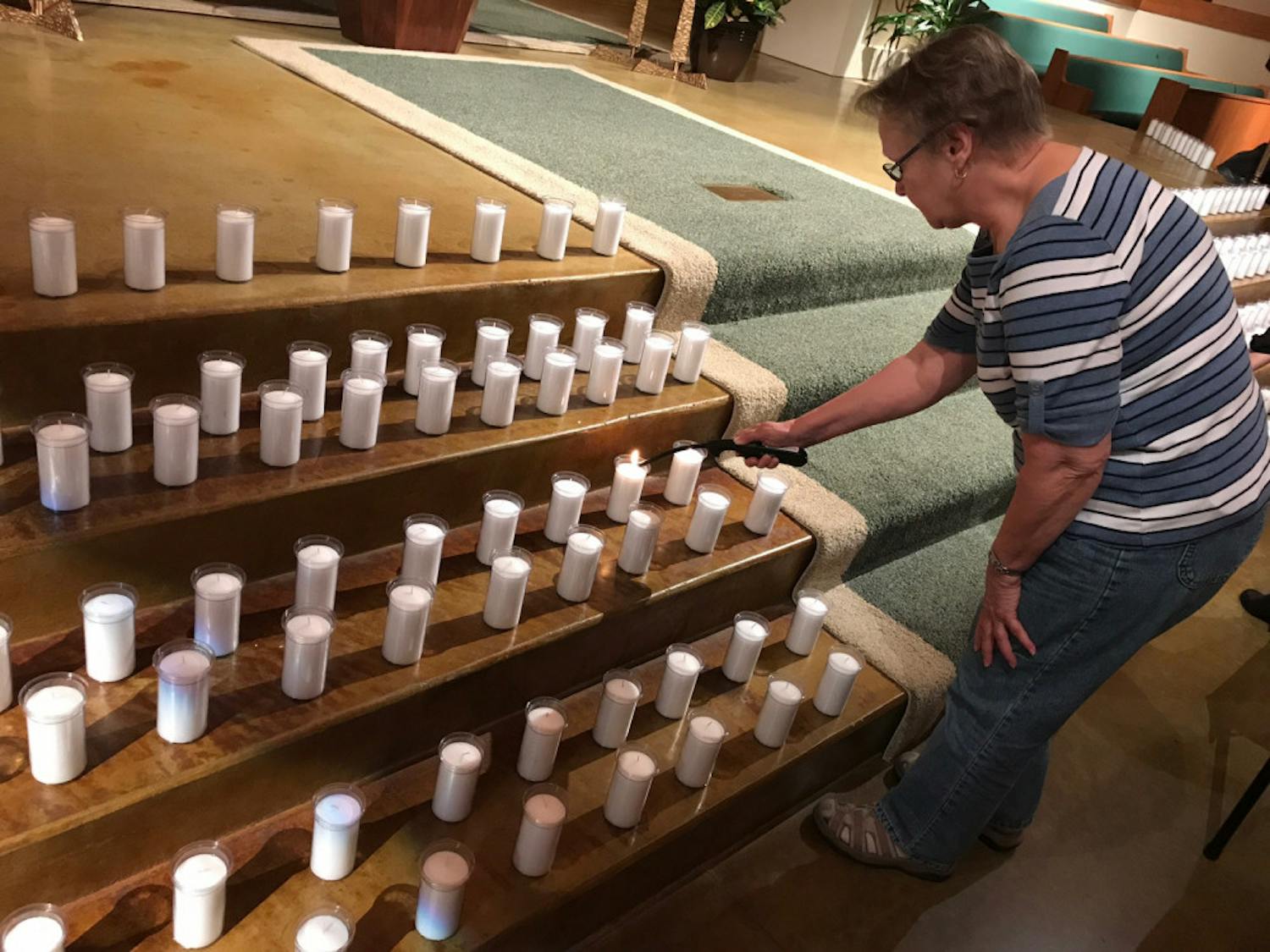Susan Johnson bends to light one of the 352 candles in St. Patrick Catholic Church, located at 500 NE 16th Ave., on Thursday night. The candles, which represented the 352 inmates on death row in Florida, were part of the church’s Cities for Life Day event.