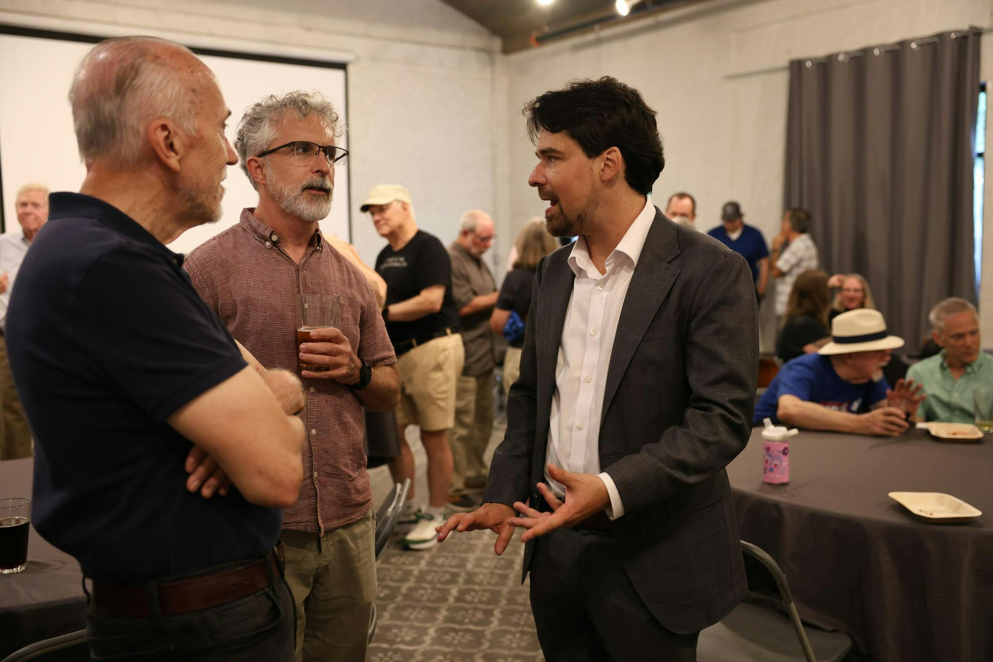 Bryan Eastman talks with Richard Allen and Wes Jones at his city commission campaign kickoff at Cypress and Grove in Gainesville, Fla., Wednesday, May 27, 2026.