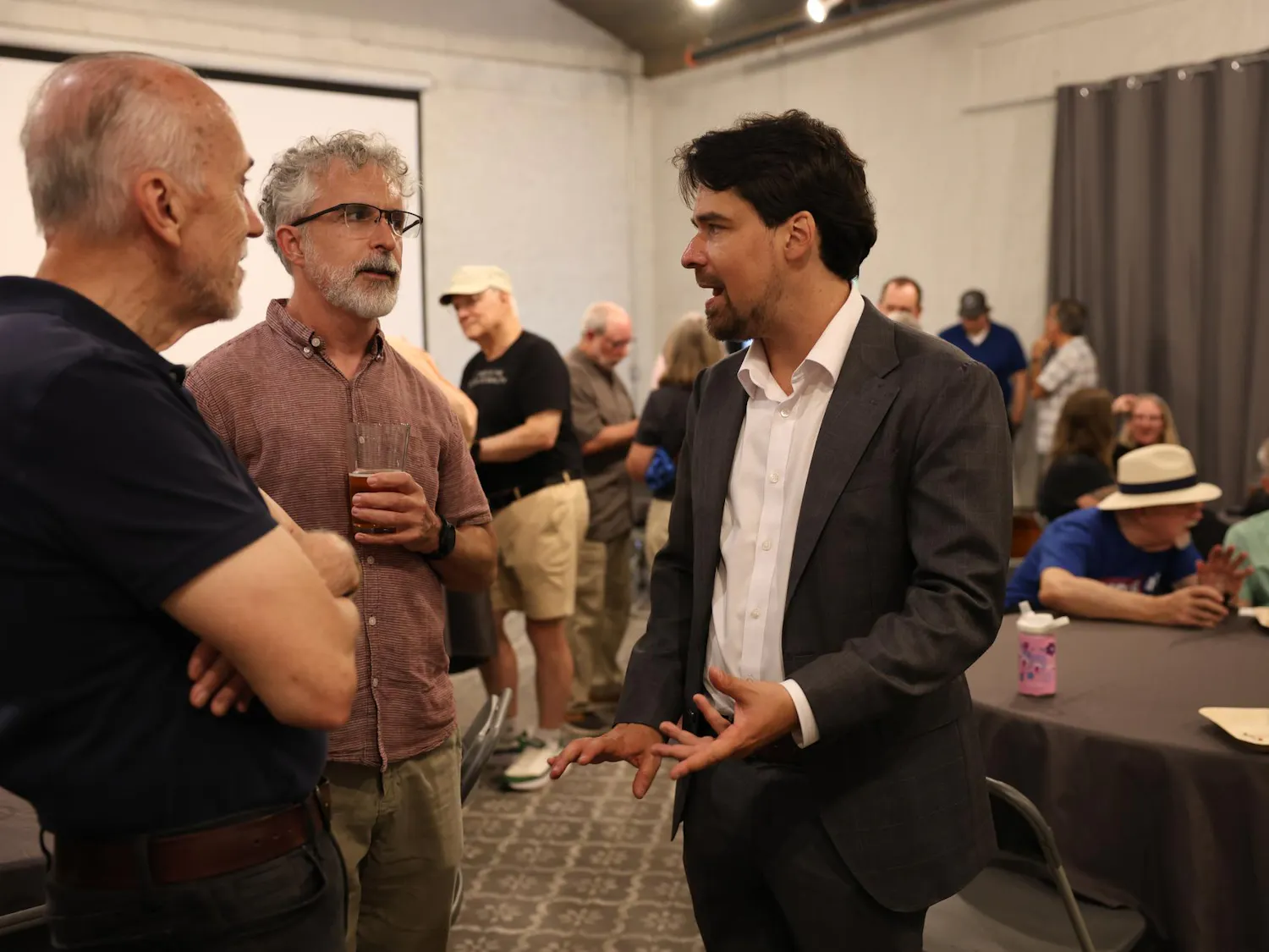 Bryan Eastman talks with Richard Allen and Wes Jones at his city commission campaign kickoff at Cypress and Grove in Gainesville, Fla., Wednesday, May 27, 2026.