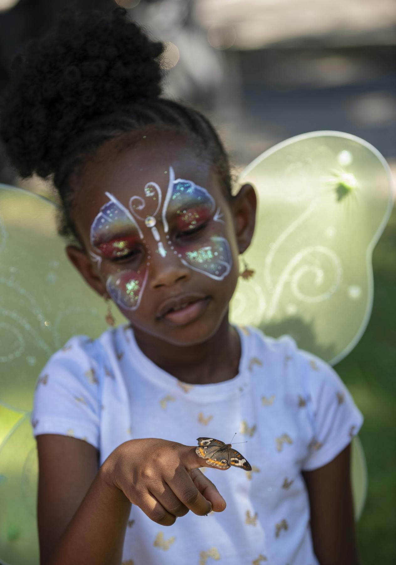 An attendee from the 2018 ButterflyFest holds a butterfly in her wings. 