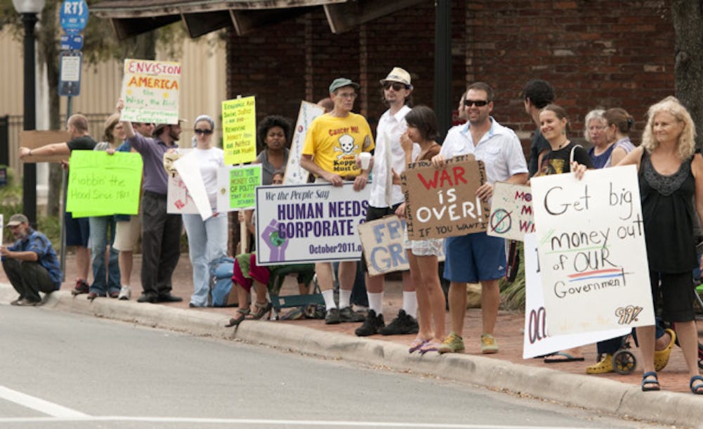 <p>Occupy Gainesville protesters line University Avenue on Wednesday. The protesters who still occupy Bo Diddley Community Plaza live off organic and local food deliveries.</p>