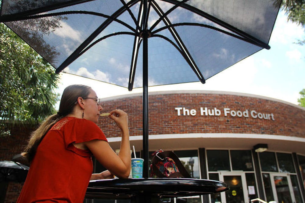 <p>Sedonia Steininger, a 32-year-old first-year entomology and nematology master’s student, eats lunch under an umbrella outside the Hub on Tuesday afternoon. Some students are choosing to avoid the Reitz Union because of construction.</p>