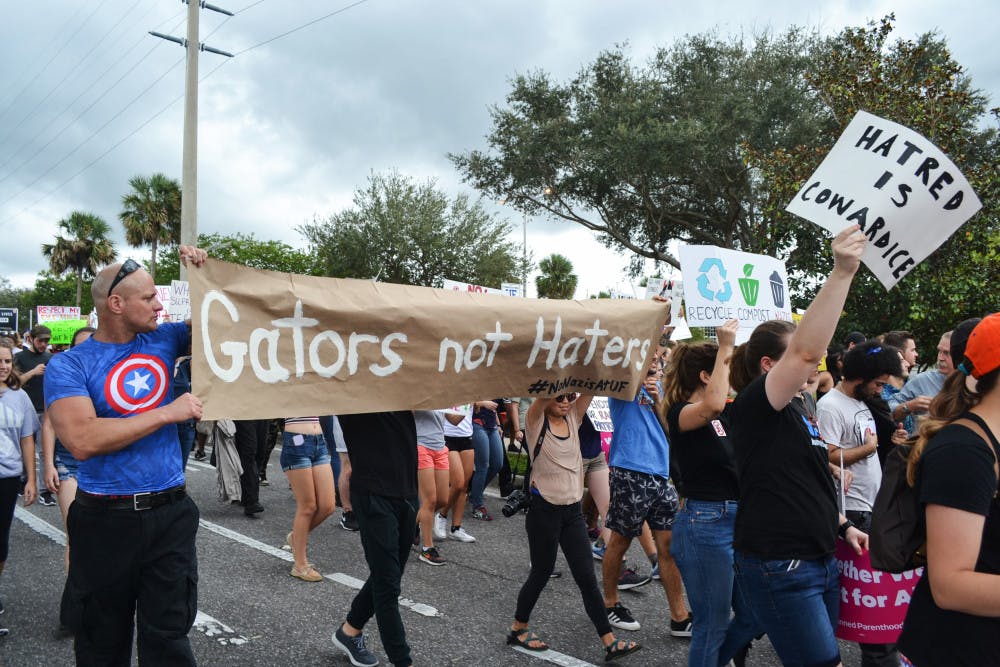 Richard Spencer protesters march toward the Phillips Center for the Performing Arts holding a “Gators not Haters” sign.