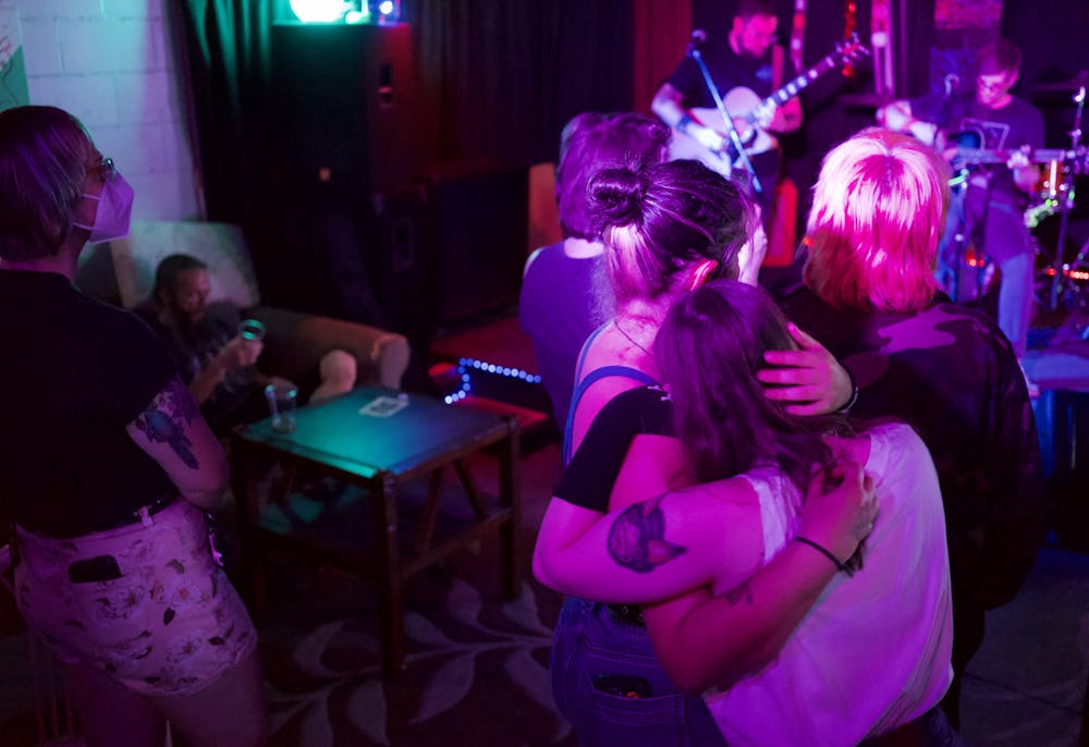 <p>Two girls hug while listening to the band Heart Prevails at the Hardback Cafe’s closing party on Saturday, May 14, 2022. </p>
