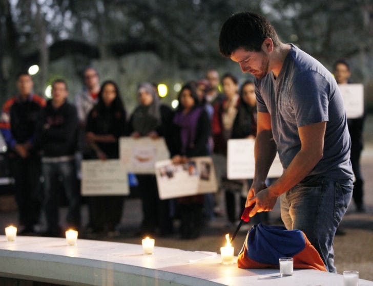 Renato Barreda, a 21-year-old UF history and political science senior, lights a candle in remembrance of dead and injured Syrian students during a vigil Wednesday night.