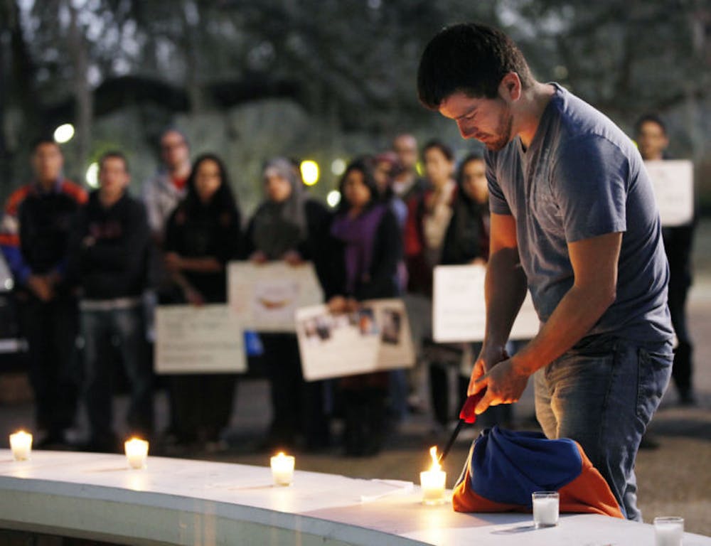<p>Renato Barreda, a 21-year-old UF history and political science senior, lights a candle in remembrance of dead and injured Syrian students during a vigil Wednesday night.</p>
