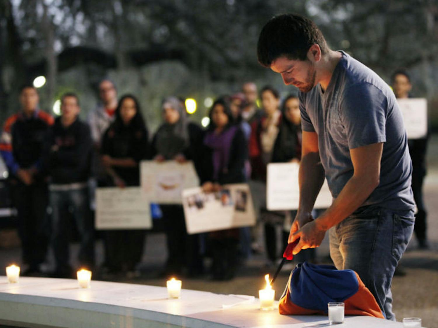 Renato Barreda, a 21-year-old UF history and political science senior, lights a candle in remembrance of dead and injured Syrian students during a vigil Wednesday night.