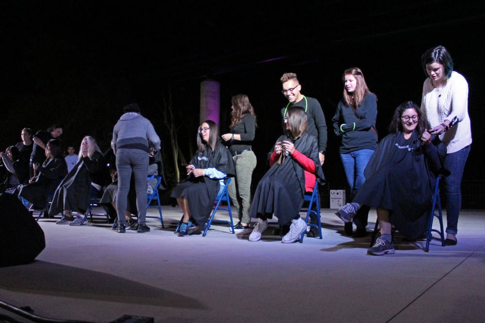 Volunteers sit on the stage on Flavet Field during Relay For Life on Saturday. The volunteers pictured were willingly donating their hair. 