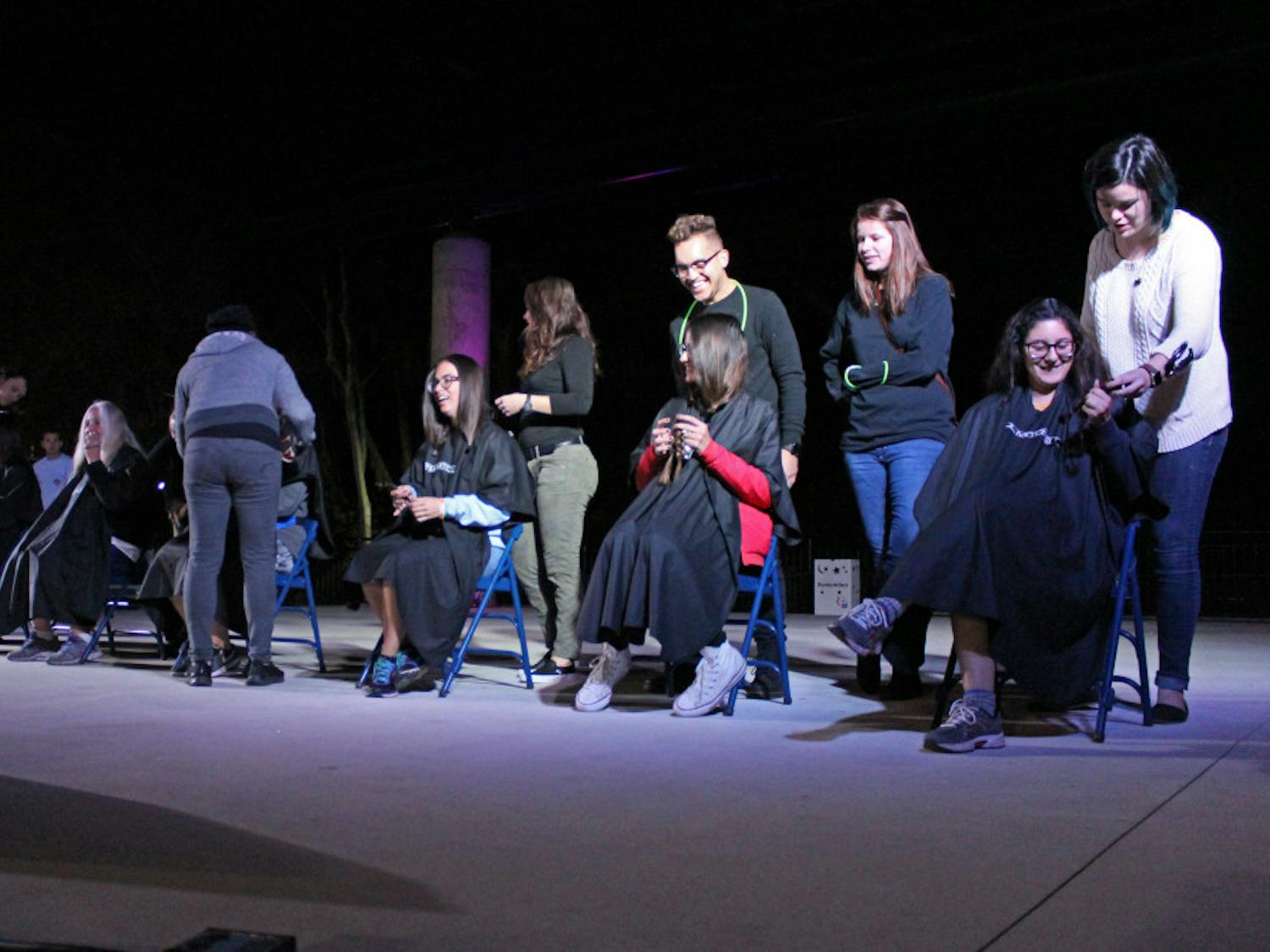 Volunteers sit on the stage on Flavet Field during Relay For Life on Saturday. The volunteers pictured were willingly donating their hair.
