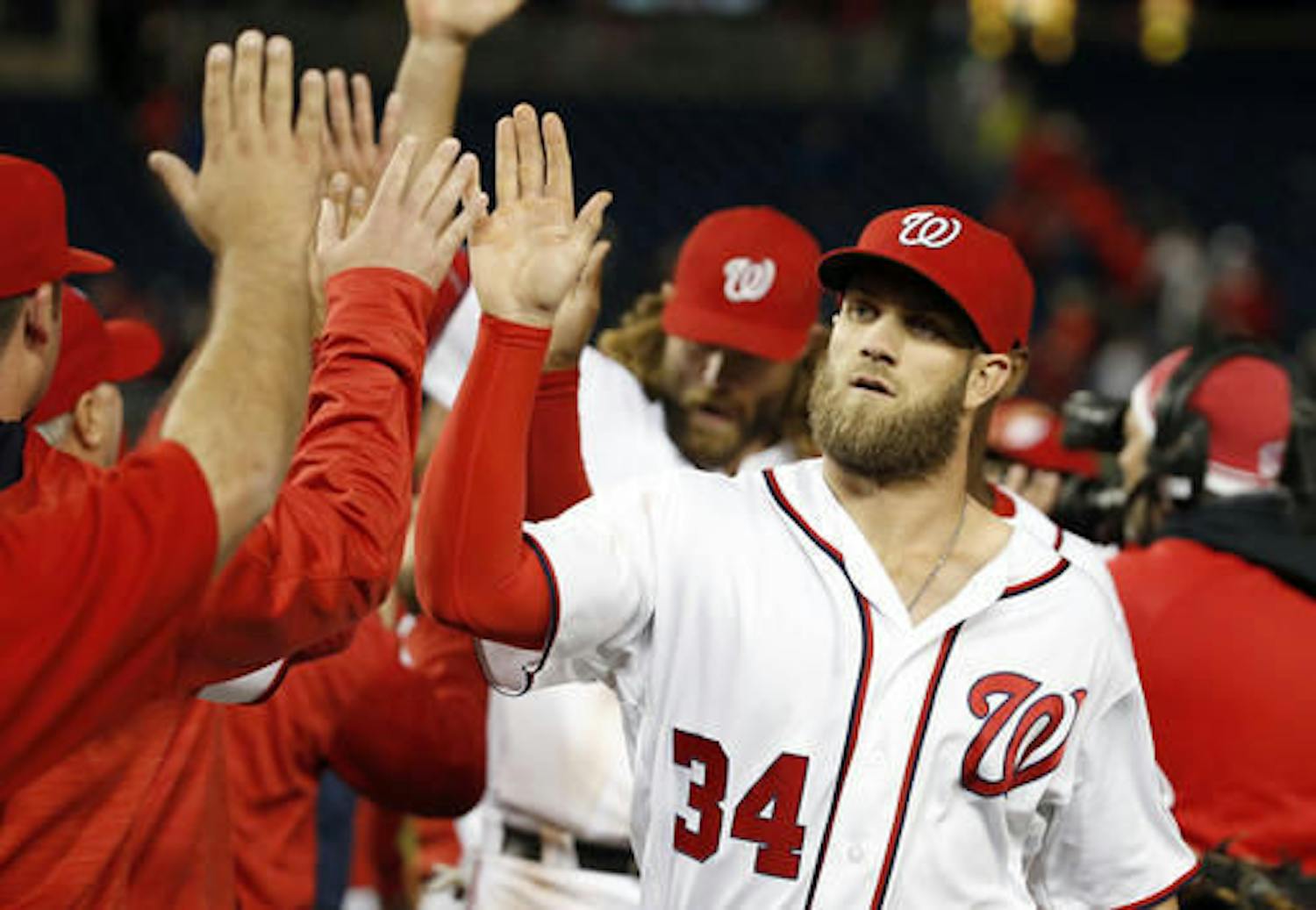 Washington Nationals' Bryce Harper (34) celebrates with teammates after a baseball game against the Atlanta Braves at Nationals Park, Tuesday, April 12, 2016, in Washington. Harper hit a two-run double in the eighth innings. The Nationals won 2-1. (AP Photo/Alex Brandon)