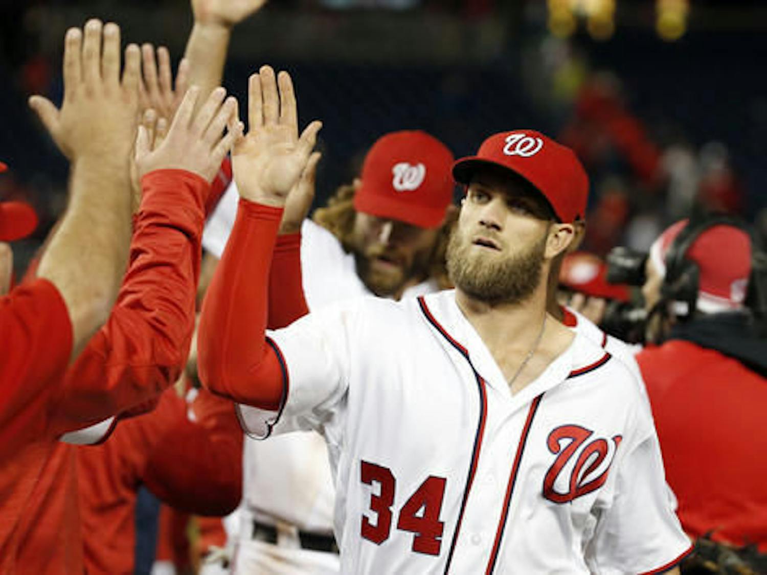 Washington Nationals' Bryce Harper (34) celebrates with teammates after a baseball game against the Atlanta Braves at Nationals Park, Tuesday, April 12, 2016, in Washington. Harper hit a two-run double in the eighth innings. The Nationals won 2-1. (AP Photo/Alex Brandon)