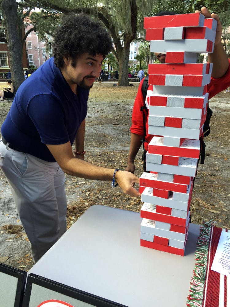 Rafael Cruzado, 27, an employee at UF’s multicultural affairs, takes a piece from Omega Delta Phi held its first “Jiant Jenga” game. Each of the 60 silver and red pieces had a fact about human trafficking written on it.