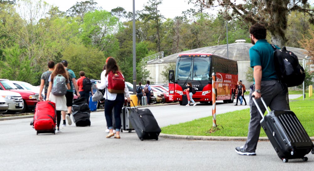 Students and other passengers walk toward a RedCoach bus to begin boarding Thursday afternoon at the Commuter Lot as UF will begin its Spring Break this upcoming week. 