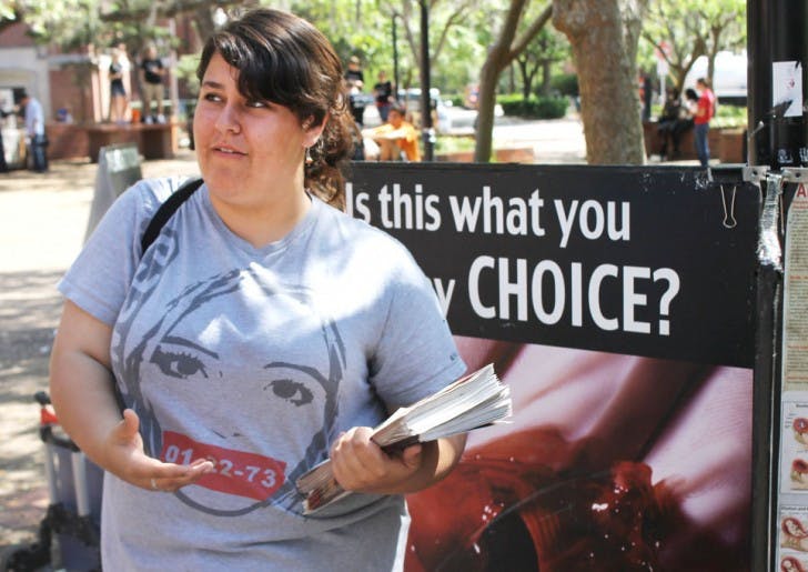 Sarah Durling, 18, of California, passes out handouts for Survivors of the Abortion Holocaust on Turlington Plaza on Tuesday afternoon. The group, which is partnered with pro-life group Created Equal, is on a nationwide tour, displaying graphic posters of mutilated fetuses to spread abortion awareness. The UF Pro-Life Alliance also displayed posters on the Plaza of the Americas. All groups will display tomorrow as well.
