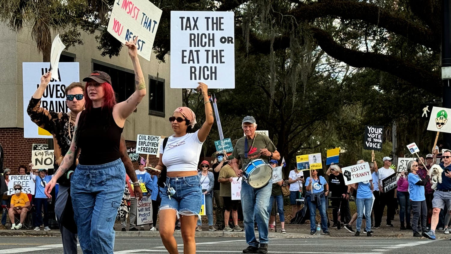 Protesters cross University Avenue holding signs criticizing the Trump administration as a part of the national “March 4th Day of Action" at a demonstration on the Corner of University Ave and Main Street on Tuesday, March 4, 2025.