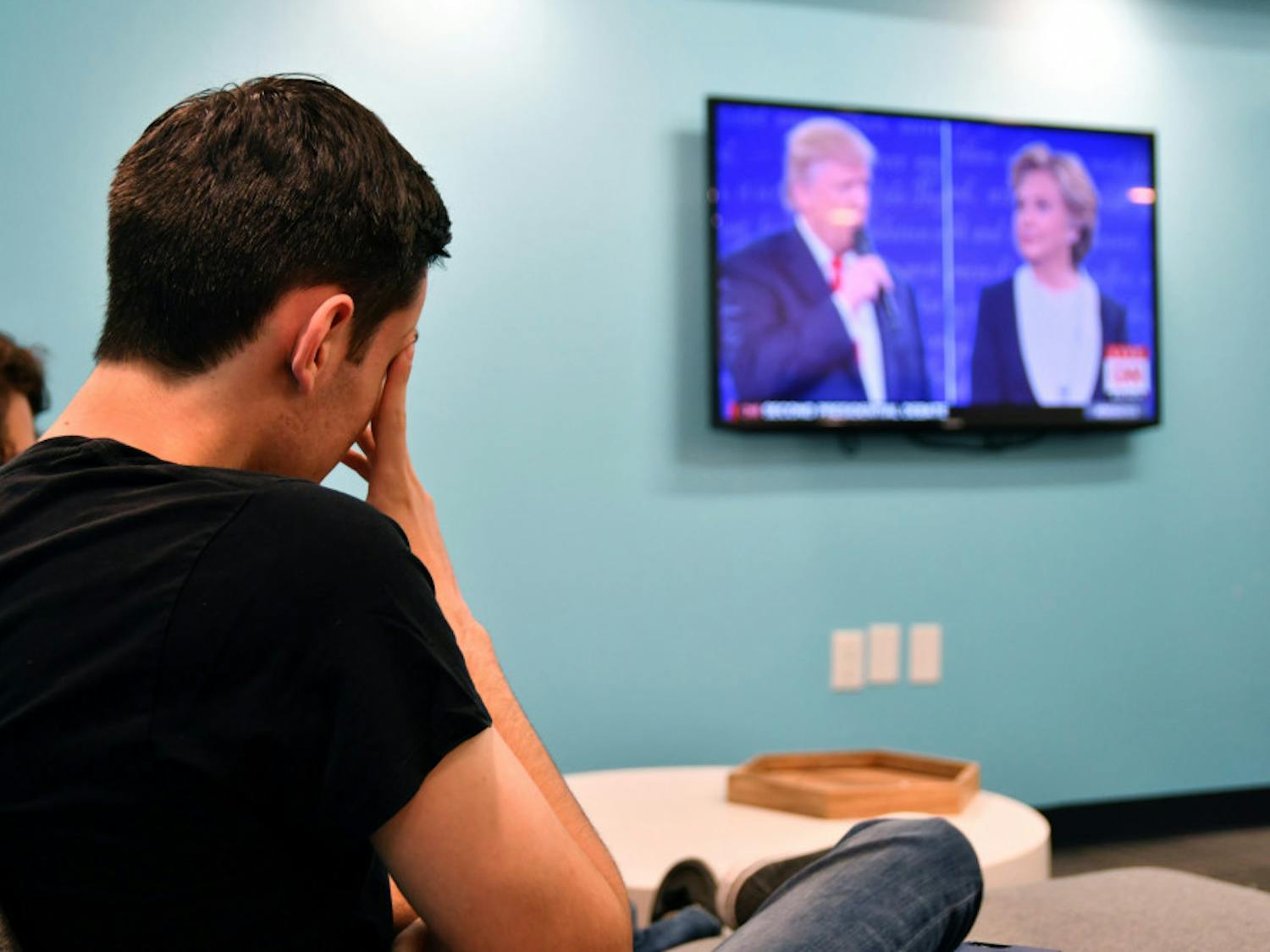 Daniel Hopin, a 20-year-old UF public relations junior, covers his face as he watches the two candidates banter back and forth during the UF College Republicans’ watch party on Sunday evening at Social 28’s south building, located at 311 SW 13th St.