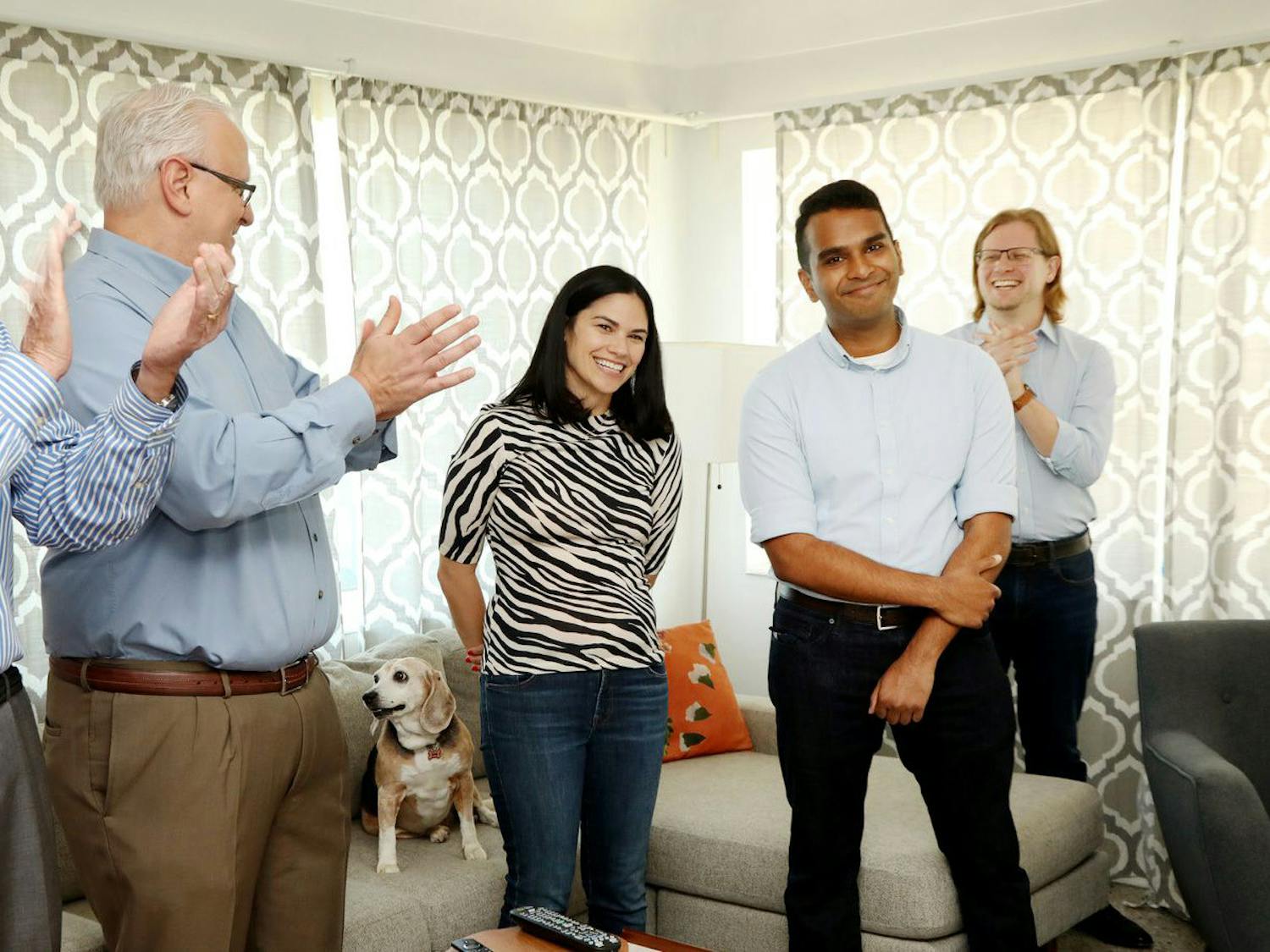 (From left to right) Paul Tash, Chairman and CEO of the Times Publishing Company, Tampa Bay Times Executive Editor Mark Katches, UF journalism professors and Times reporters Kathleen McGrory and Neil Bedi, and former Deputy Editor of Investigations Adam Playford cheer on McGrory and Bedi as they are announced as the winners of the Pulitzer Prize for Local Reporting on June 11, with the McGrory family pet beagle, Susan, sitting on the couch.