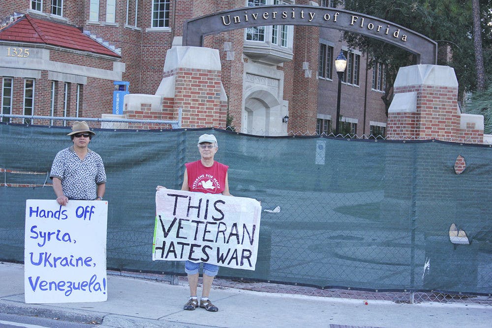 Vietnam veteran Mary Bahr (right), 69, and volunteer Ku Wang (left), 63, hold signs protesting war at the corner of Northwest 13 Street and West University Avenue on Veterans Day.