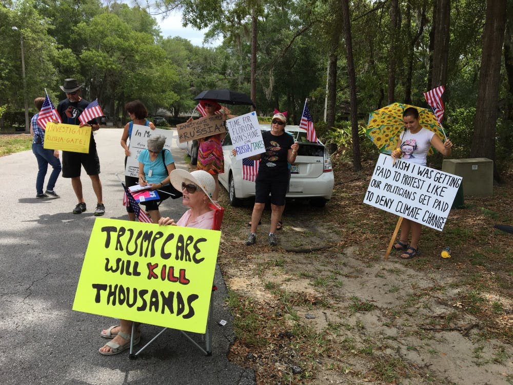 <p dir="ltr"><span>Gainesville residents meet outside U.S. Rep. Ted Yoho's office during their lunch hour on Tuesday afternoon to protest by waving signs stating their political opinions.</span></p>