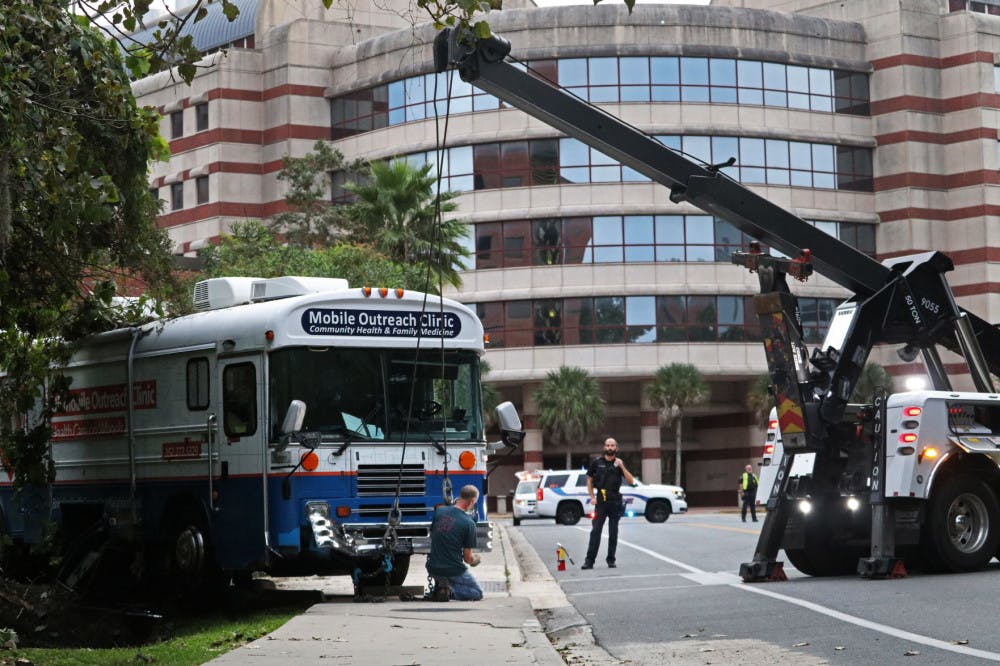 UFPD Officer Roberts watches as tow workers pull a UF Mobile Outreach Clinic bus from a ditch on the side of Newell Drive.