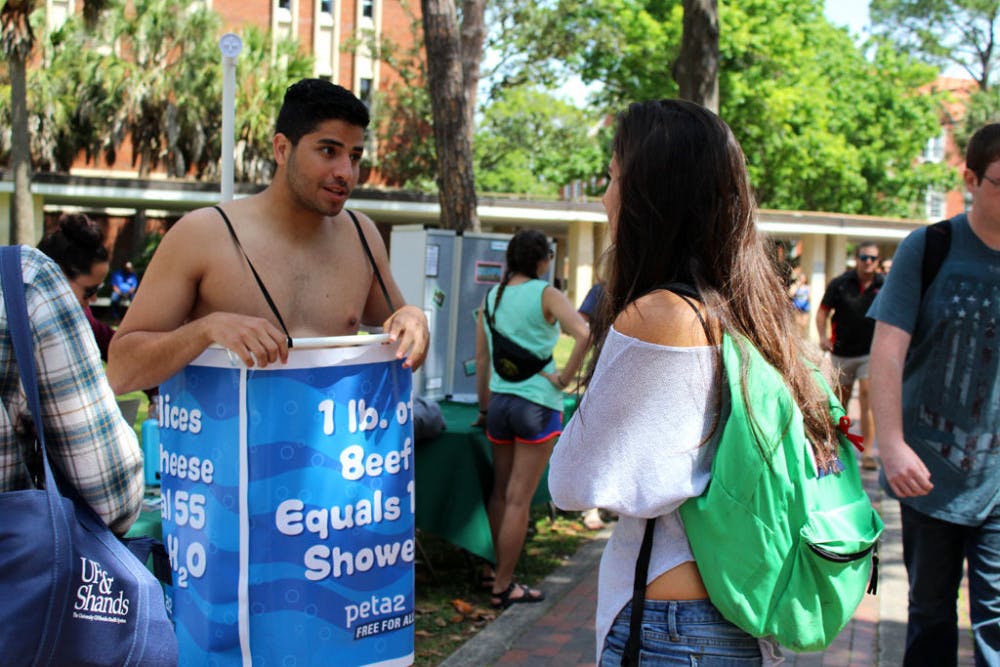 Manny Rutinel, a 21-year-old UF microbiology and cell science and economics senior, left, promotes the Student Animal Alliance by promoting veganism. Rutinel said it's easy to remember to turn off a faucet while you soap or brush your teeth, but animal agriculture accounts for more environmental problems than any other sector of the environment. "In order to go green, you have to eat green," he said.