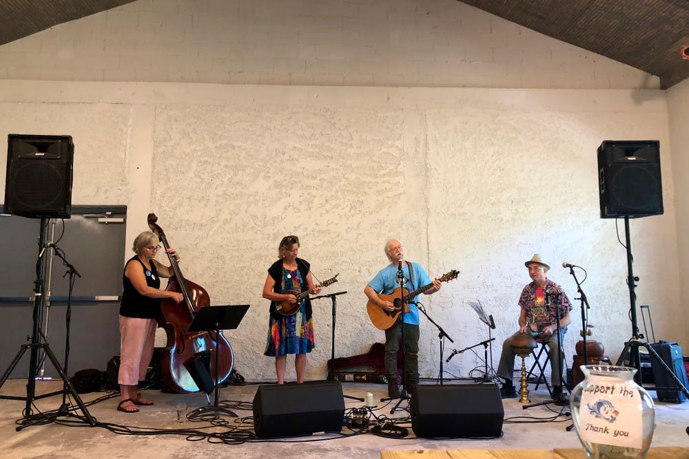Art Crummer, a local folk band, plays “You Are My Sunshine,” while a crowd relaxes on wooden benches. Kelly Hayes / Alligator Contributing Writer 