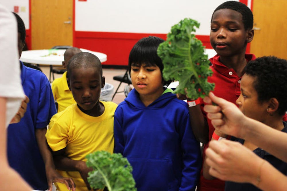 <p>Children learn about fresh produce from Fostering Sustainable Behavior: Local Food Systems UF honors class students Wednesday afternoon at the Porters Community Center.</p>