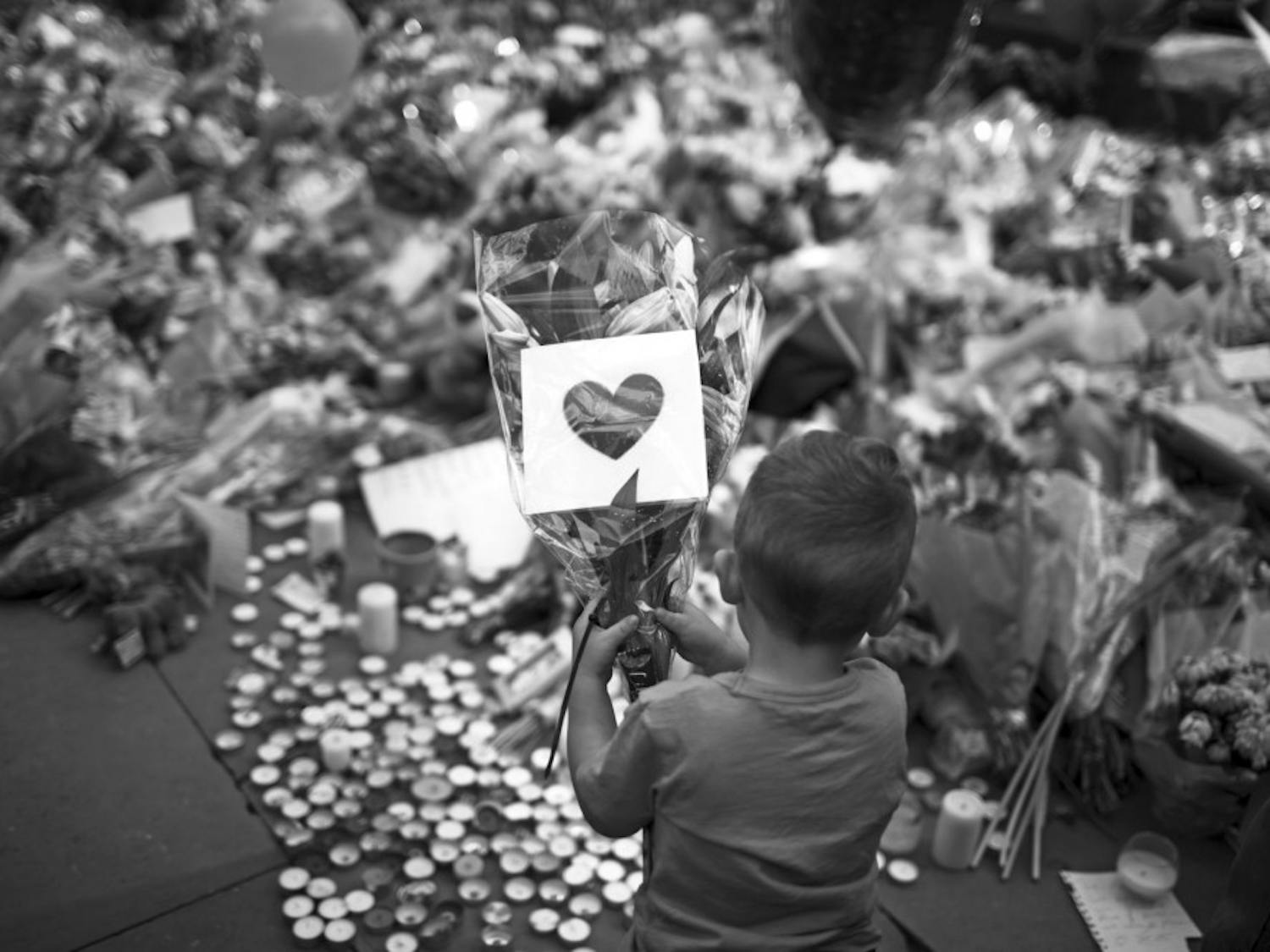 A child places flowers in a square in central Manchester, England, on Wednesday after the suicide bomb attack at an Ariana Grande concert that left 22 people dead and many more injured as it ended on Monday night at the Manchester Arena.
