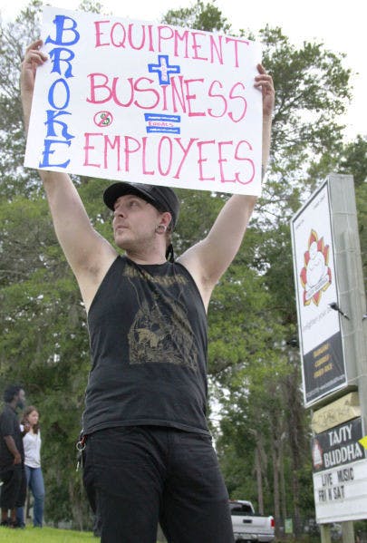 Striking Tasty Buddha cook Dustin Horn protests outside the restaurant Saturday. Employees say there has been a history of bounced checks.
&nbsp;