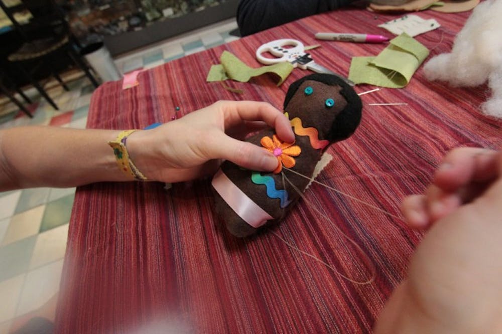 <p>Gainesville resident Crystal Sorrow, 34, sews up Zoe, one of the seven dolls she made at Wild Iris Books for the Comfort Doll Project, a national project that makes dolls for domestic abuse victims. "I wanted to make her cheerful so she would be a bright spot for a battered woman," Sorrow said.</p>