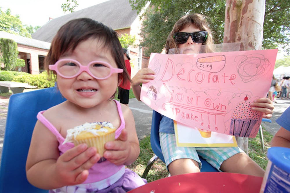 <p>Gainesville resident Mae, 3, shows off a cupcake she iced at the Santa Fe College Spring Arts Festival in 2012 while Jodie, 8, holds a sign promoting the cupcake-decorating to raise money for FUMPers, the preschool of First United Methodist Church.</p>