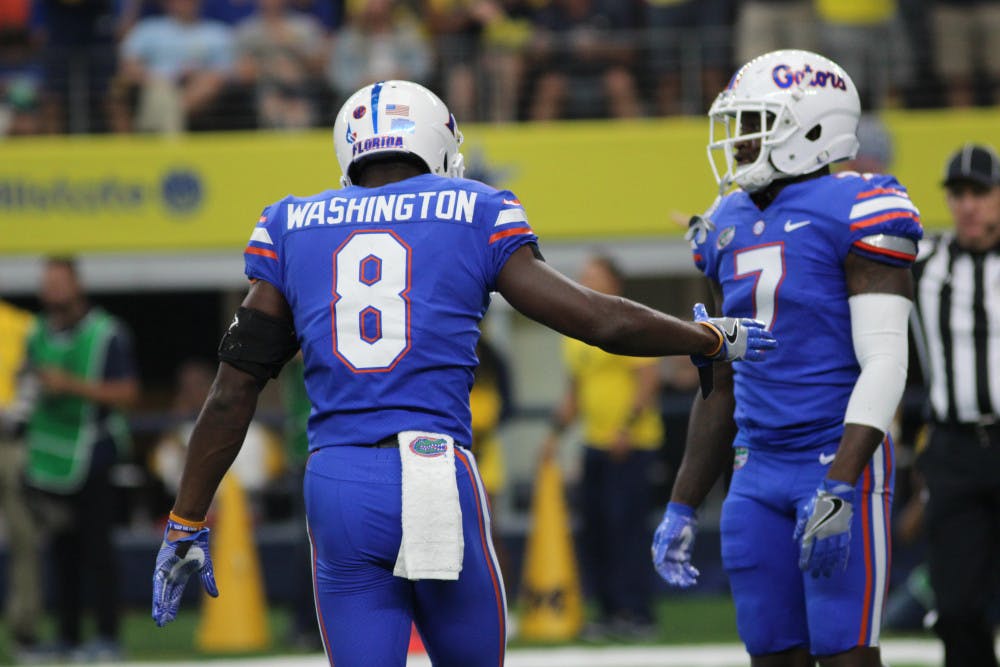 Nick Washington goes to high-five Duke Dawson during UF's 33-17 loss against Michigan on Saturday at AT&amp;T Stadium in Arlington, Texas.
