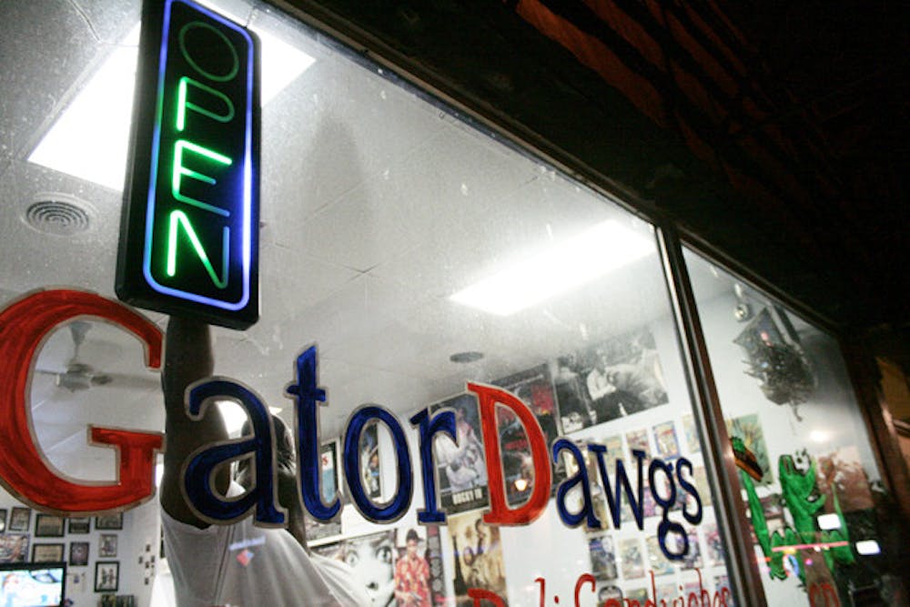 <p>Otis Britt, owner of Gator Dawgs on West University Avenue, turns off the open sign at the front of the restaurant. Gator Dawgs will officially close Sunday.</p>