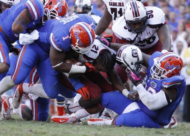 Defensive tackle Omar Hunter (right) rips off Marcus Lattimore’s helmet during Florida’s 44-11 win against South Carolina on Saturday at Ben Hill Griffin Stadium.&nbsp;