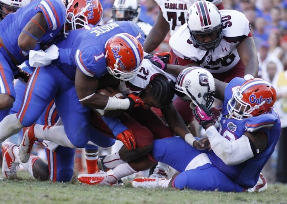 <p>Defensive tackle Omar Hunter (right) rips off Marcus Lattimore’s helmet during Florida’s 44-11 win against South Carolina on Saturday at Ben Hill Griffin Stadium.&nbsp;</p>