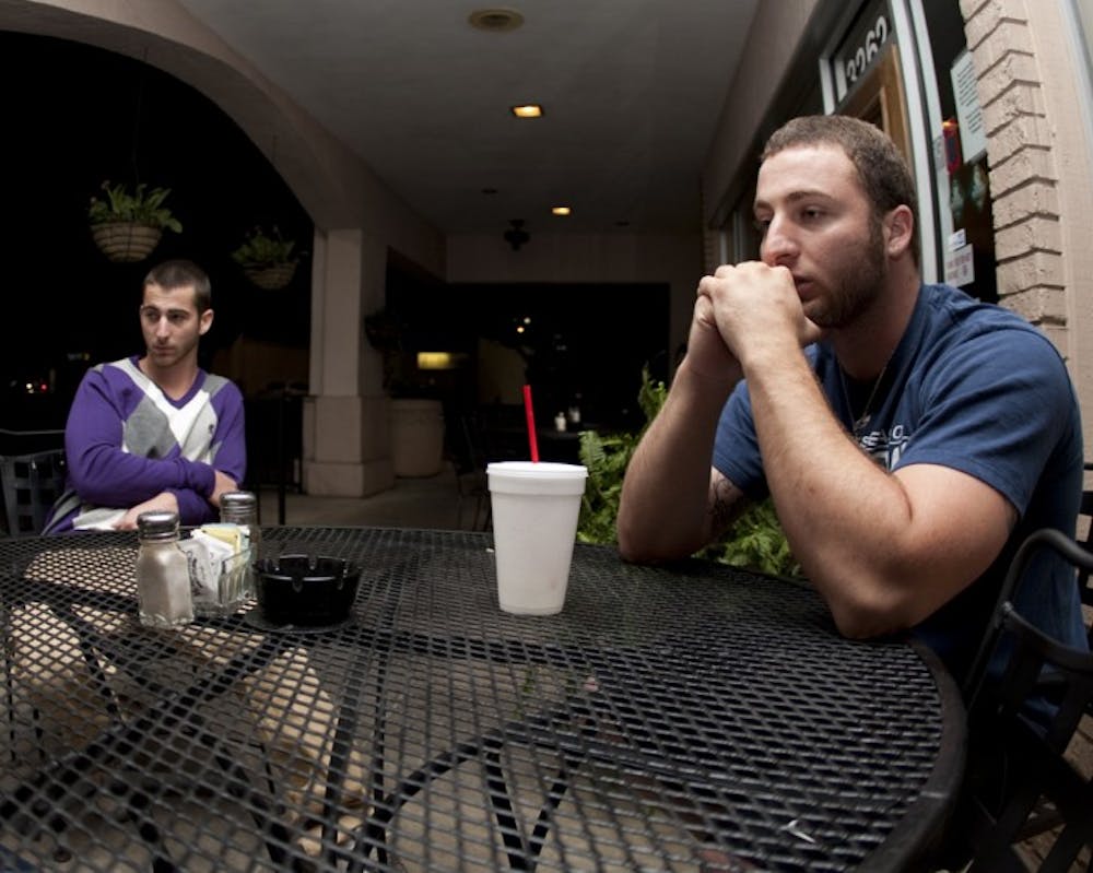 <p>Jude Rizzo, 21, right, sits with his 19-year-old brother, Joel Rizzo, at McAlister’s Deli. Jude told police he shot and killed his roommate, Michael Crace, in self-defense on April 2.</p>