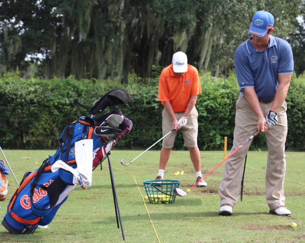 <p>Maintenance staff members Scott Dowling, back, and Mike Brown, front, line up to hit at the driving range of UF’s Mark Bostick Golf Course on Wednesday.</p>