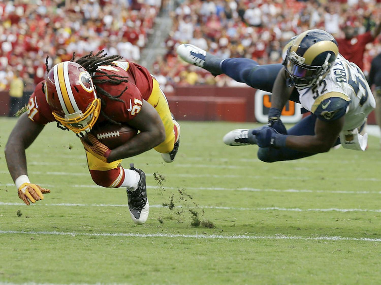 In this photo taken Sept. 20, 2015, Washington Redskins running back Matt Jones (31) dives for extra yardage after breaking a tackle by St. Louis Rams outside linebacker Alec Ogletree (52) during the second half of an NFL football game in Landover, Md.