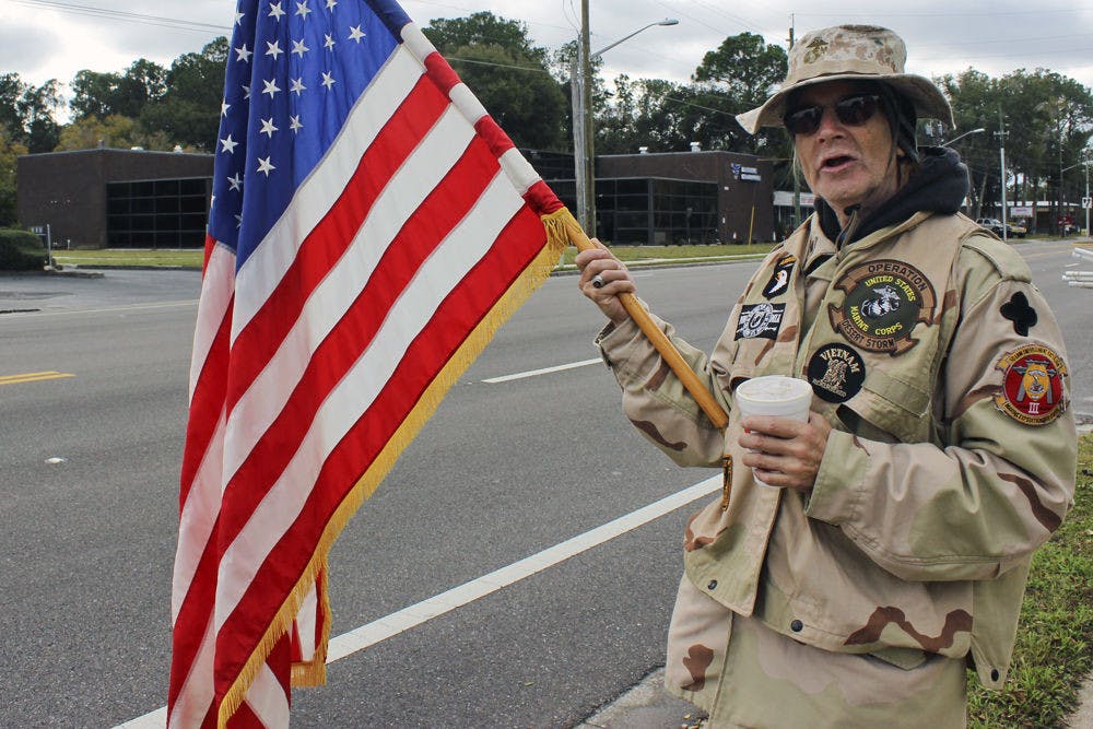 <p>Cody Anderson, a member of the Military Support Group of Alachua County, holds a flag during the protest against Clock Restaurant on Saturday morning. “I felt it was important to support Mr. Woods,” Anderson said. “I felt that the way he was treated was not only illegal but immoral.”</p>