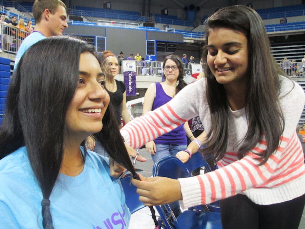 <p class="p1"><span class="s1">Aishwarya Potdar, a 21-year-old applied physiology and kinesiology junior, gets her hair cut by her 15-year-old sister, Amruta Potdar, for Relay for Life. The event was held Friday night through Saturday morning in the Stephen C. O’Connell Center.</span></p>