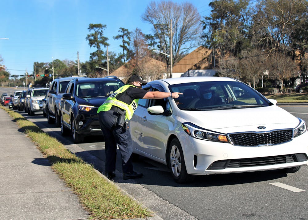 J. Evans, a Gainesville Police Department officer, directs traffic into Malcom Randall VA Medical Center on Monday, Jan. 18, 2021. A long line of traffic formed outside the hospital as Alachua County residents 65-years-old and older waited to receive COVID-19 vaccines.