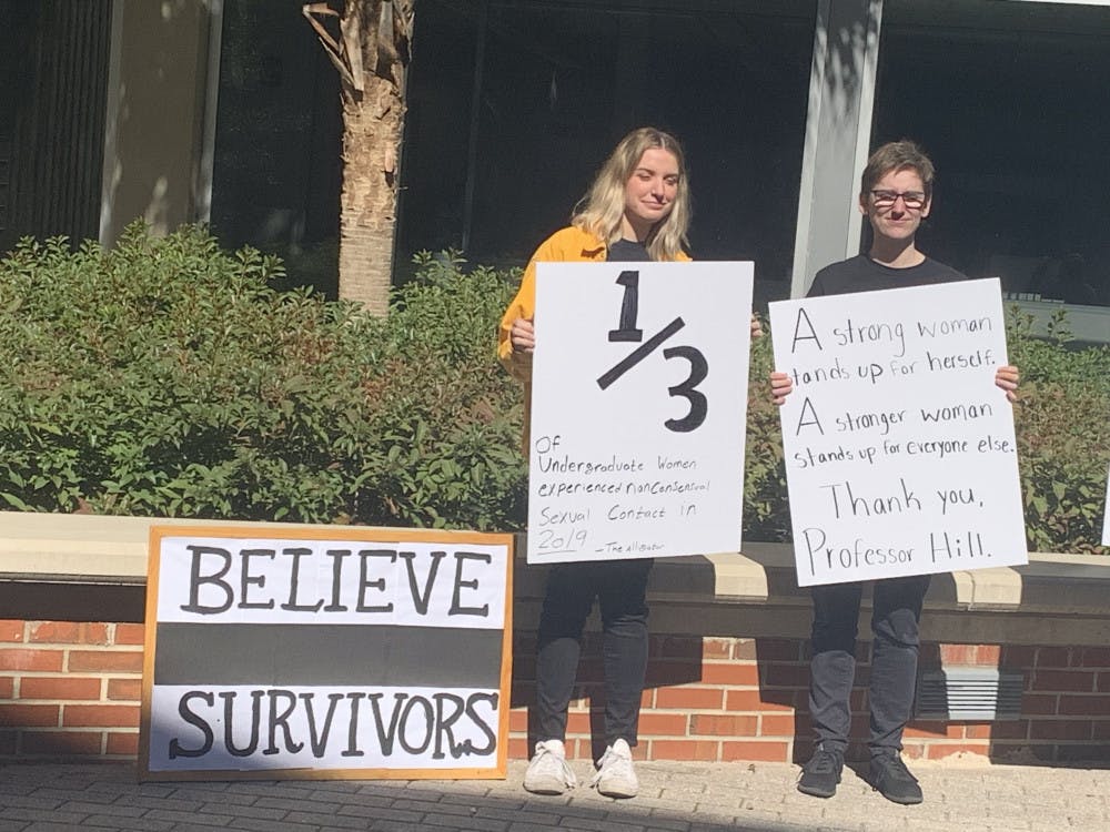 <p>UF law students Anne Marie Tamburro and Brenna Cameron stand for a moment of silence in solidarity with victims of sexual violence at the protest against Supreme Court Justice Clarence Thomas on Tuesday.</p>