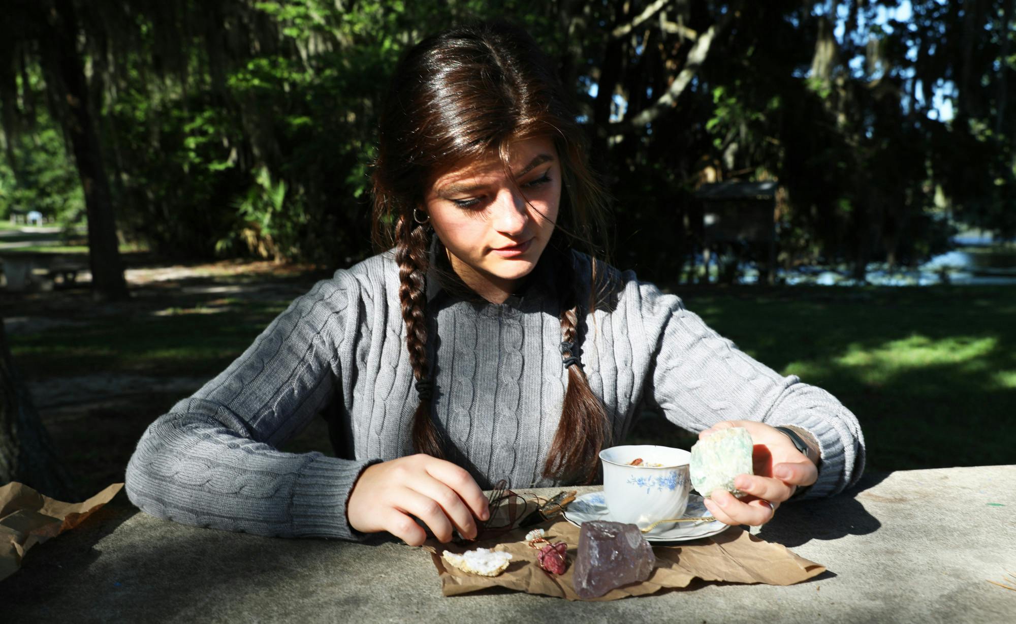 Aubrey Dolbeck, 21, a Gainesville business owner, looks at products she made on Friday, June 11, 2021. She sometimes searches for gems at Lake Alice.
