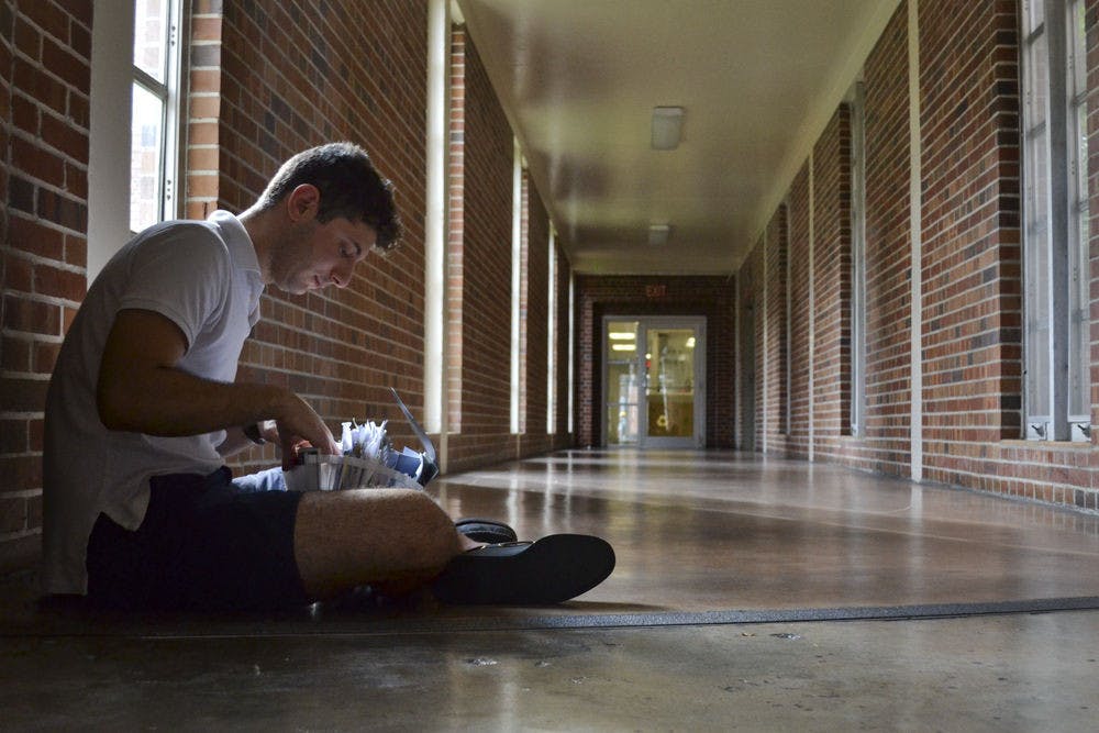 Nicholas Nourieh, a UF biology junior and Syrian immigrant, flips through papers that hold memories of his past childhood, lost friends and a broken home country in Graham Hall on Nov. 3, 2015. After being away for three years, the 20-year-old visited his neighborhood in Homs, Syria, last summer and found destroyed buildings and spirits.