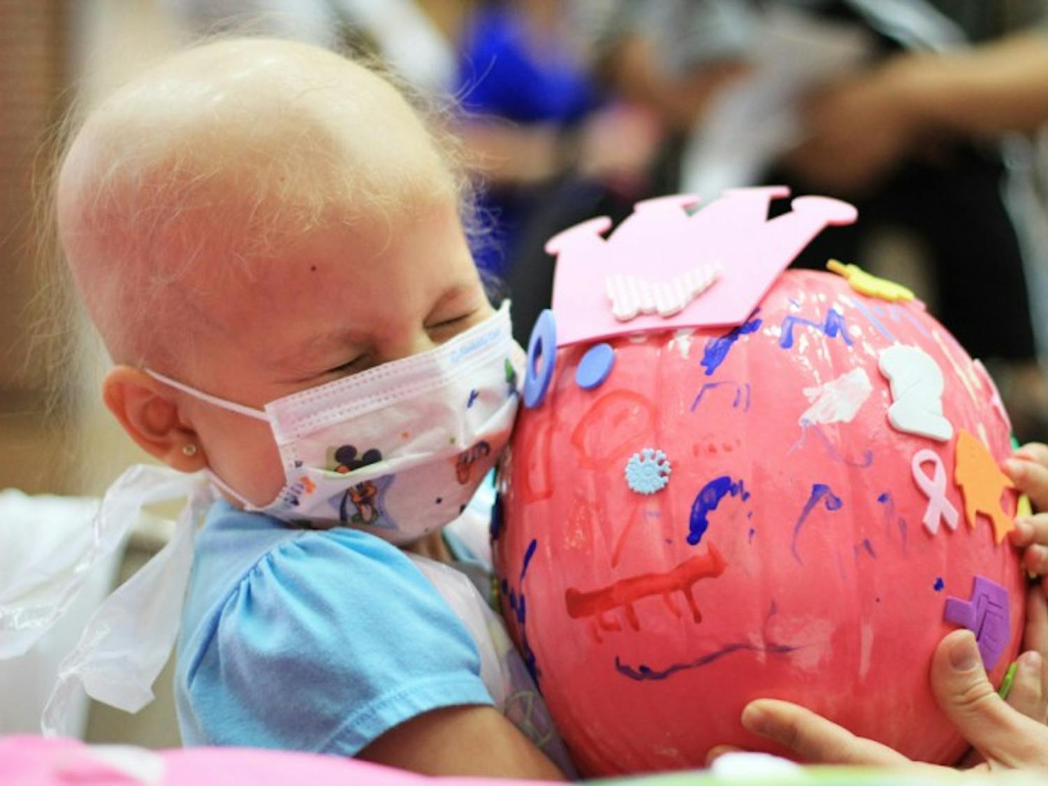 Madison, a 4-year-old undergoing treatment for leukemia at Shands Hospital for Children at UF, holds her pink pumpkin on Wednesday morning as part of an event for patients and families.
